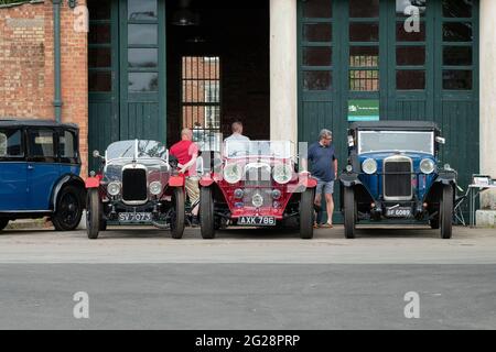 Vintage cars outside a workshop at the Bicester Heritage Centre super scramble event. Bicester, Oxfordshire, England Stock Photo