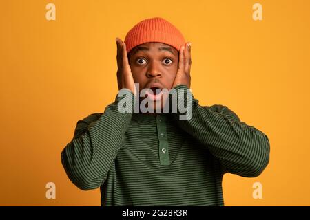 Portrait Of Terrified Young Black Man Touching Head In Shock Stock Photo