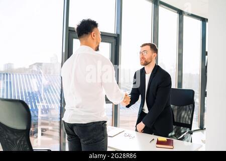 Two businessmen shake hands in office Stock Photo