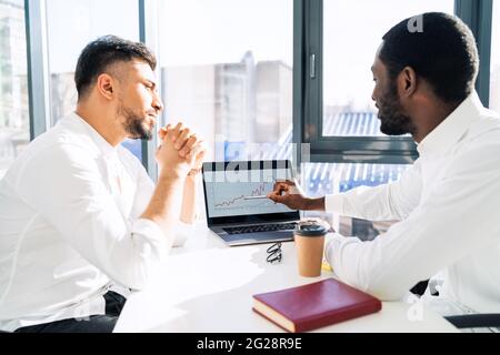 Black office worker shows the boss the growth of the company on diagram in laptop Stock Photo