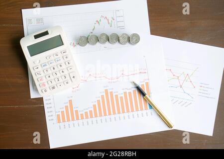 Calculator, coins and pen laying on chart. Concept of finance. Stock Photo