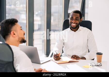Business colleagues talking while sitting at the table in the office Stock Photo