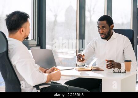 Business colleagues talking while sitting at the table in the office Stock Photo