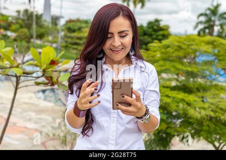 latina woman smiling at the smart phone in a meeting. Stock Photo