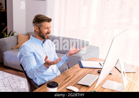 Shot of businessman sitting behind his laptop and having discussion and online meeting in video call.  Business meeting online. Teamwork. Stock Photo