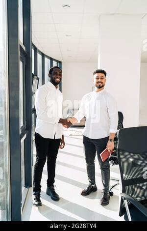 Two multiracial businessmen shake hands in office Stock Photo