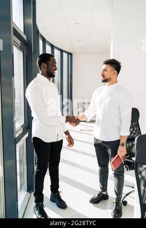 Two multiracial businessmen shake hands in office Stock Photo
