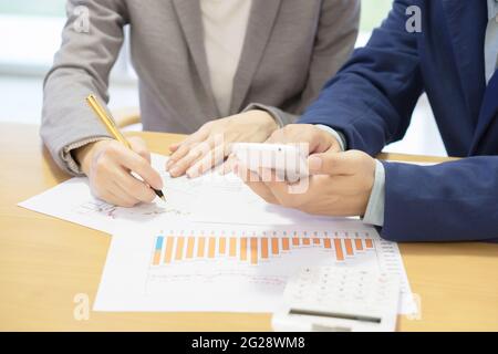 two colleagues and business documents on office table with smart phone and graph business with social network Stock Photo