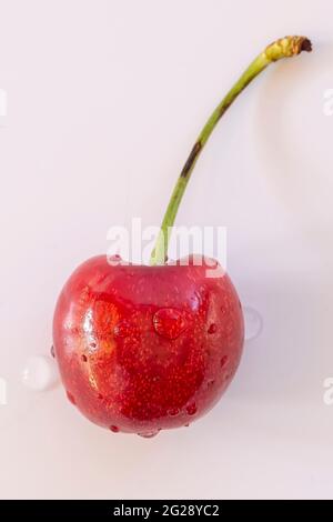 A red cherry with water droplets on the surface on a white background Stock Photo