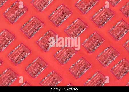 Shopping carts, mini shopping carts pattern background, isolated on red, top view. Stock Photo