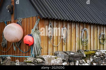 A selection of ropes and buoys hung on a shed at Croig Harbour on the Isle of Mull Stock Photo