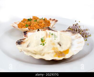 plate with two scallops prepared in a different way, Galician style and with béchamel sauce and olive oil Stock Photo