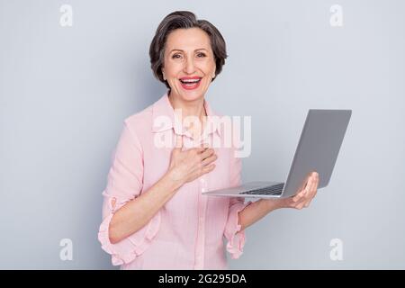 Portrait of attractive cheerful woman holding in hands using laptop company development laughing isolated over gray pastel color background Stock Photo