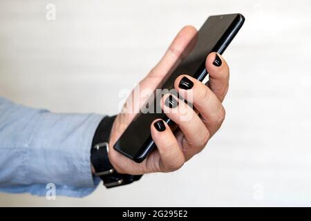Close-up image of male hands using smartphone. searching or social networks concept, hipster man typing an sms message to his friends. Man with painte Stock Photo