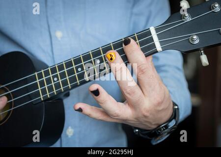 Rock musician plays on hawaiian guitar. Practicing and having fun alone. Young musician in room. reggae guitar. An informal young guy holds a musical Stock Photo