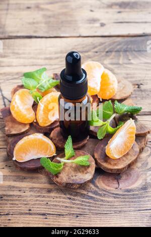 Aromatic tangerine oil in a dark bubble, cosmetic oil from Mandarin on a wooden background, copy space Stock Photo