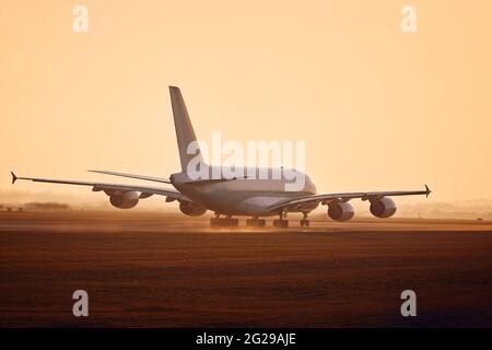 Huge airplane taking off from airport runway at golden sunset. Stock Photo