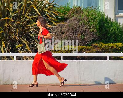 A woman in a red dress walks through Brighton Stock Photo