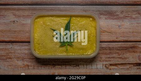Marijuana butter on wooden table with dark green leafs Stock Photo