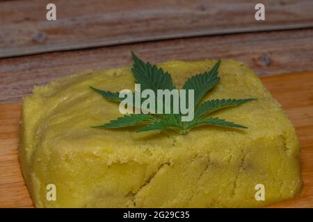 Marijuana butter on wooden table with dark green leafs Stock Photo