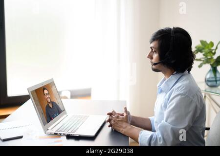 Two indian male office employee talking online via video connect on the laptop, business partners discussing tasks, men colleagues involved in video meeting on the distance. Video call concept Stock Photo