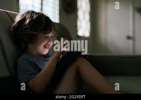 Boy smiling while using digital tablet at home Stock Photo