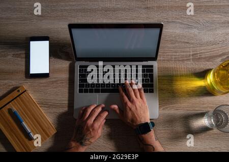 Overhead view of businessman using laptop computer and smart phone at office desk Stock Photo