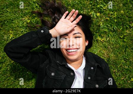 Overhead of a young latin woman lying on the grass and having fun Stock Photo