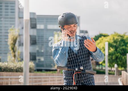 Young businessman riding on electric scooter and talking on a sm Stock Photo