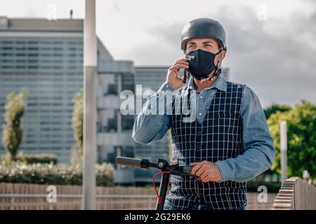 Young businessman riding on electric scooter and using smartphon Stock Photo