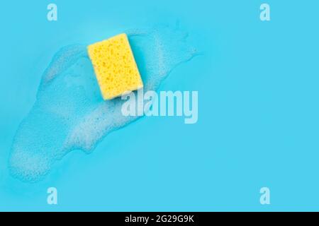 Yellow sponge with foam on blue background Stock Photo