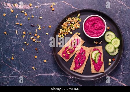 Vegetarian, vegan snack - beetroot hummus, sprouted grains, cucumber, and whole grain crisps. Stock Photo