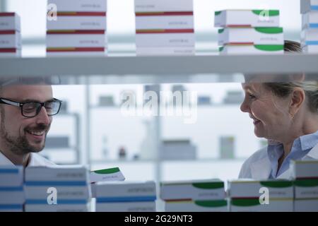 Pharmacists is working. Man and woman wearing medical uniform. People look through the patches in pharmacy. Stock Photo