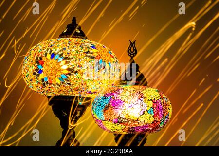 Illuminated Turkish Moroccan handmade stain glass lamps. Vibrant and colourful with unique light flare flashes, trails, streaks running through. Antiq Stock Photo