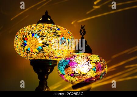 Illuminated Turkish Moroccan handmade stain glass lamps. Vibrant and colourful with unique light flare flashes, trails, streaks running through. Antiq Stock Photo