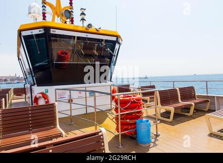 A passenger ferry's upper deck with wheelhouse, with no passengers, under clear blue sky. Horizon in the background Stock Photo