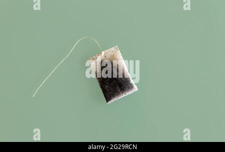 Top view of A dry unused teabag with no label card isolated on green glass surface Stock Photo