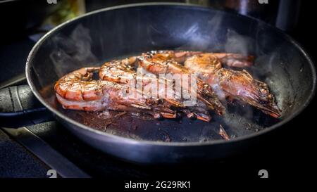 Grilled prawn in a frying pan on a dark background. Seafood appetizer. Preparation of delicious food. Stock Photo