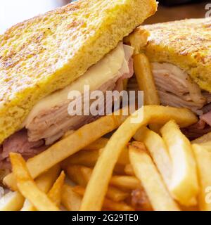 A monte cristo sandwich sits on a white plate at a diner.  Served with French fries. Stock Photo