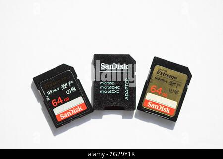 Three Sandisk SD memory cards are on a white background, top view selective focus macro shot. Sandisk is a Western Digital brand. Stock Photo