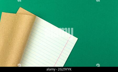 Exercise book notebook on green table, school and education concept background with lined paper, copy space, top view Stock Photo