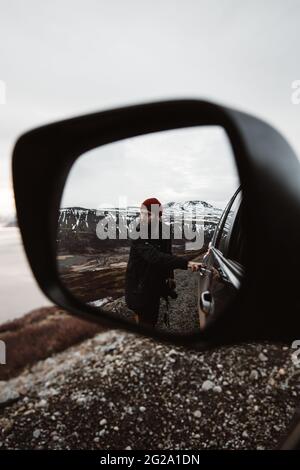 Contemplative bearded male hiker in black hoodie standing on rough mountain summit and observing picturesque highlands in twilight in Seville Spain Stock Photo