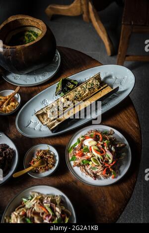 From above served round wooden table with different appetite dishes of mix of tropical fruits and vegetables in composition with seafood and herbs pre Stock Photo