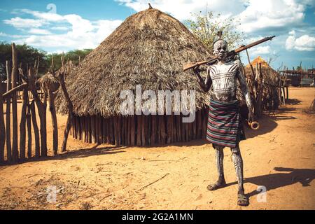 man with painted body holding a shotgun in Karo tribe village. Omo Valley, Ethiopia Stock Photo