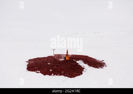 Rusty water fountain installed on red ground in white snowy terrain on cold winter day in Iceland Stock Photo