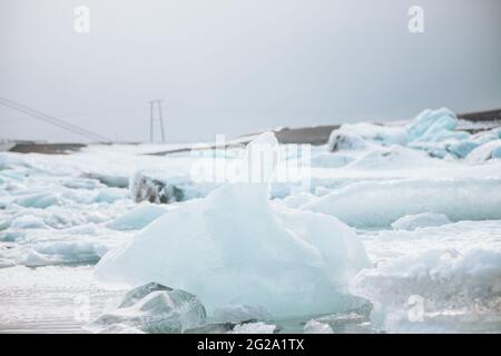 From above of white chunks of ice on calm lake water with remote snowy mountains and cloudy sky on background in Iceland Stock Photo