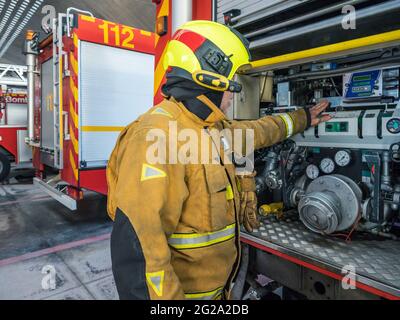 anonymous Equipped fireman standing and using an engine into fire truck Stock Photo