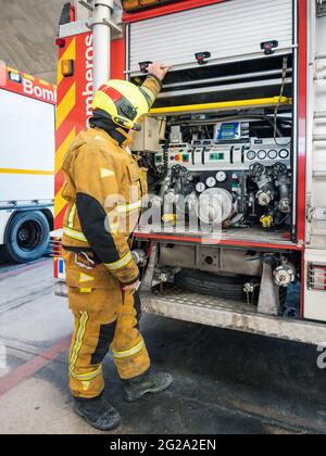 anonymous Equipped fireman standing and using an water engine into fire truck Stock Photo