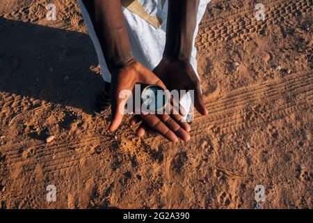 Unrecognizable African person holding retro compass in hands over dry sand of Sahara Desert Stock Photo