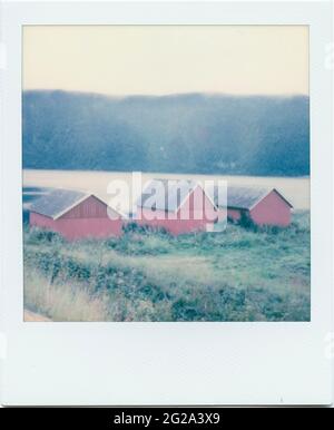 Row of small red house located near a lake and gray sky in majestic countryside Stock Photo